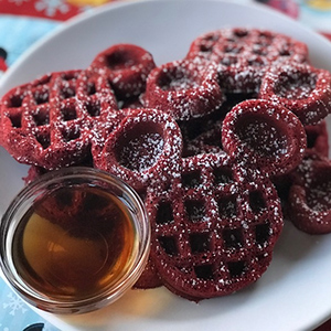 plate of red velvet waffles in the shape of mickey mouse ears