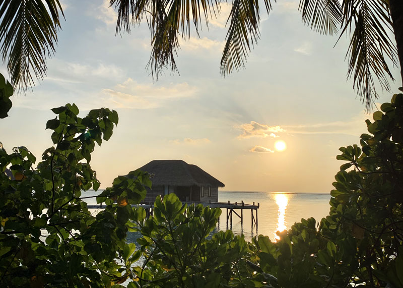 Sunset over a water villa in Conrad Maldives Rangali Island hotel resort